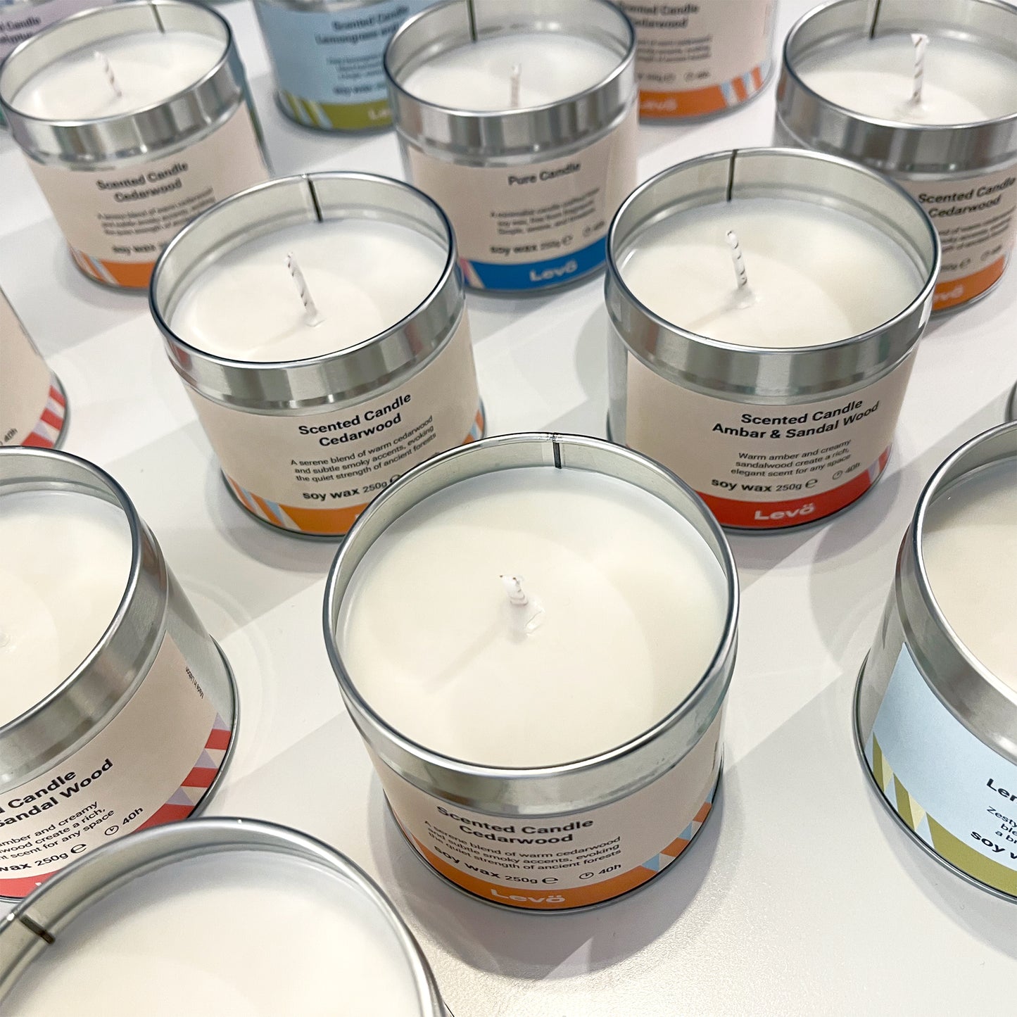 Scented candles in metal tins with labels on a white surface