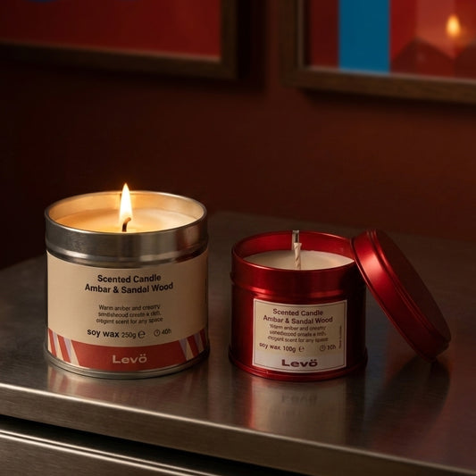 Two scented candles from the brand 'Levo' on a reflective surface with a warm glow.