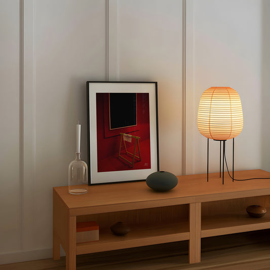 Wooden shelf with decorative items including a framed fine art photography, lamp, and vase against a neutral wall.