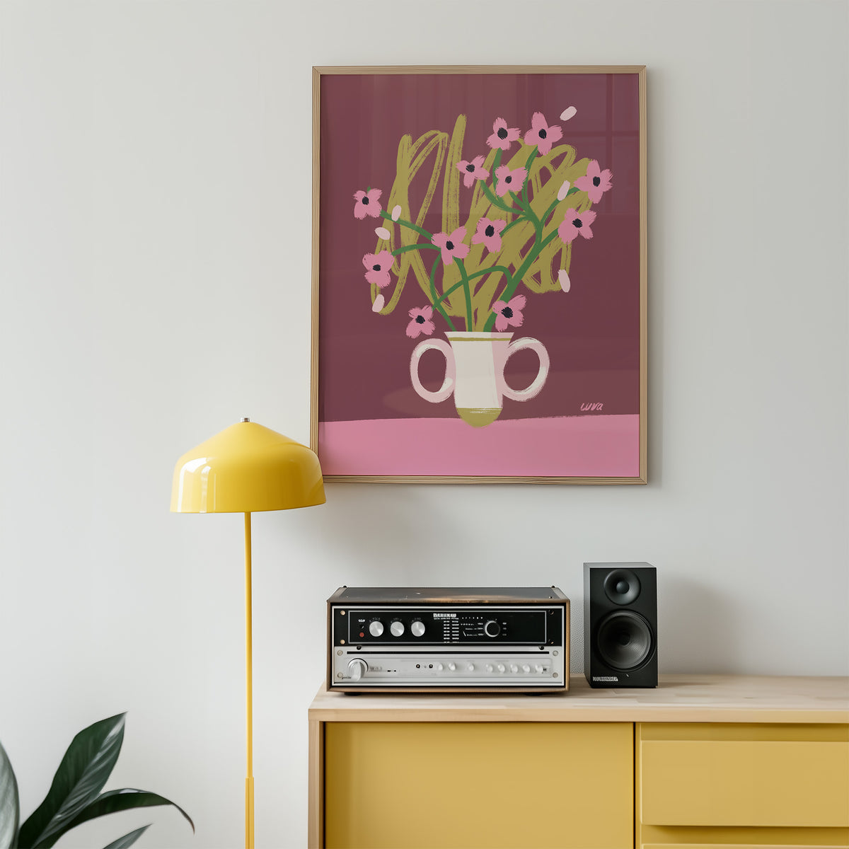 Framed artwork of flowers on a wall above a yellow cabinet with stereo equipment.