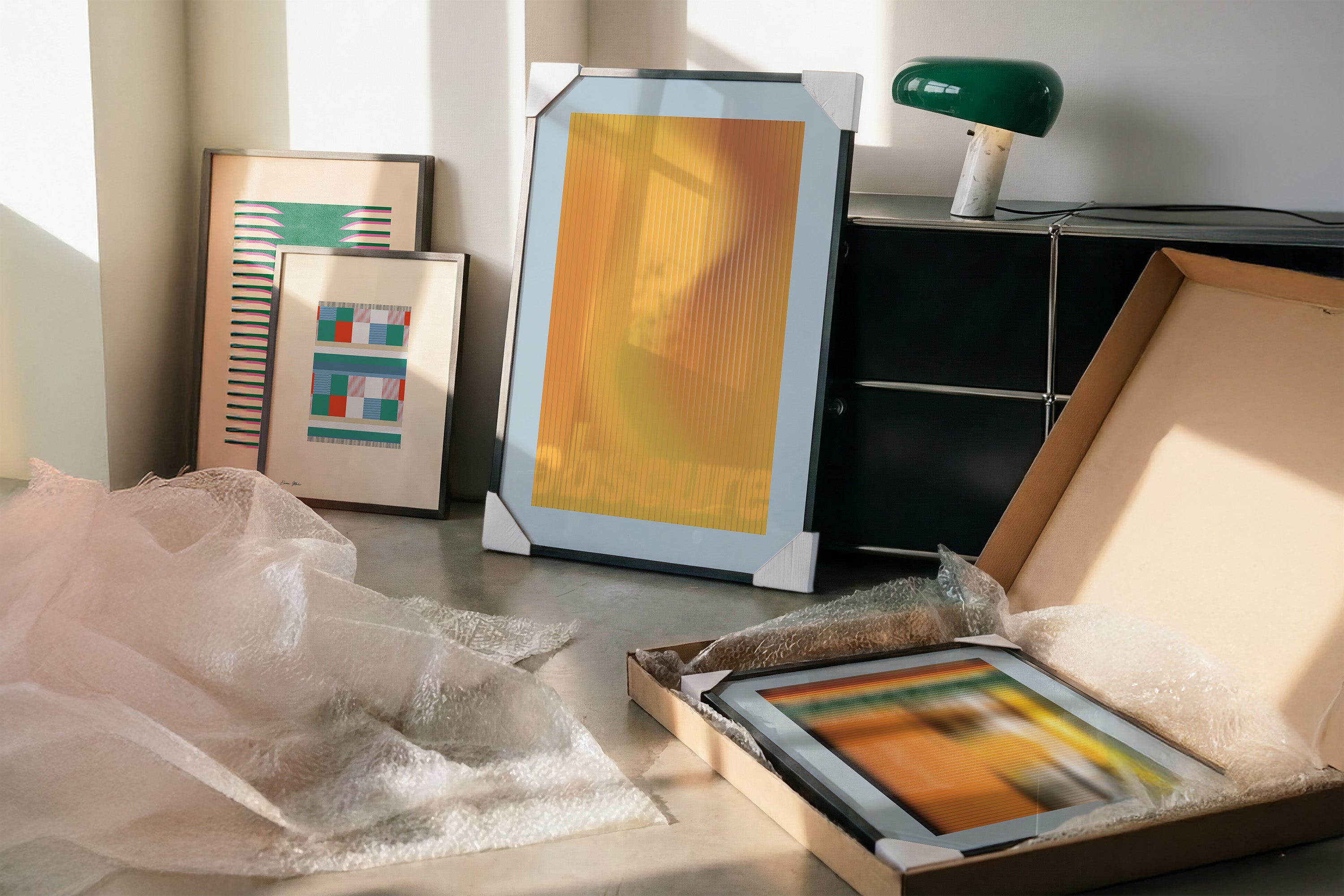 Framed artwork by Levö on a table with a lamp and other items in the background