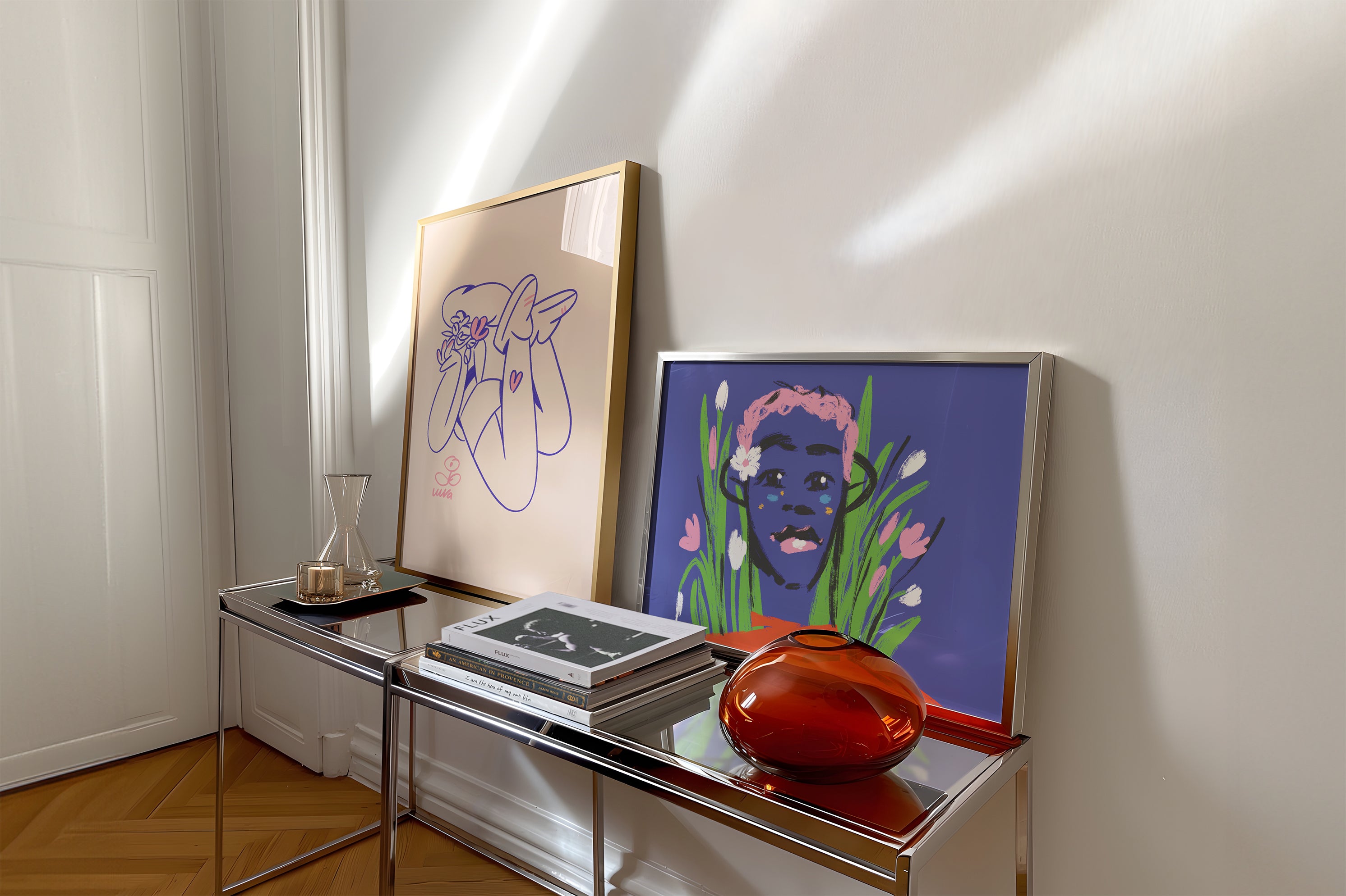 Two framed artworks on a table against a white wall.