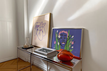 Two framed artworks on a table against a white wall.