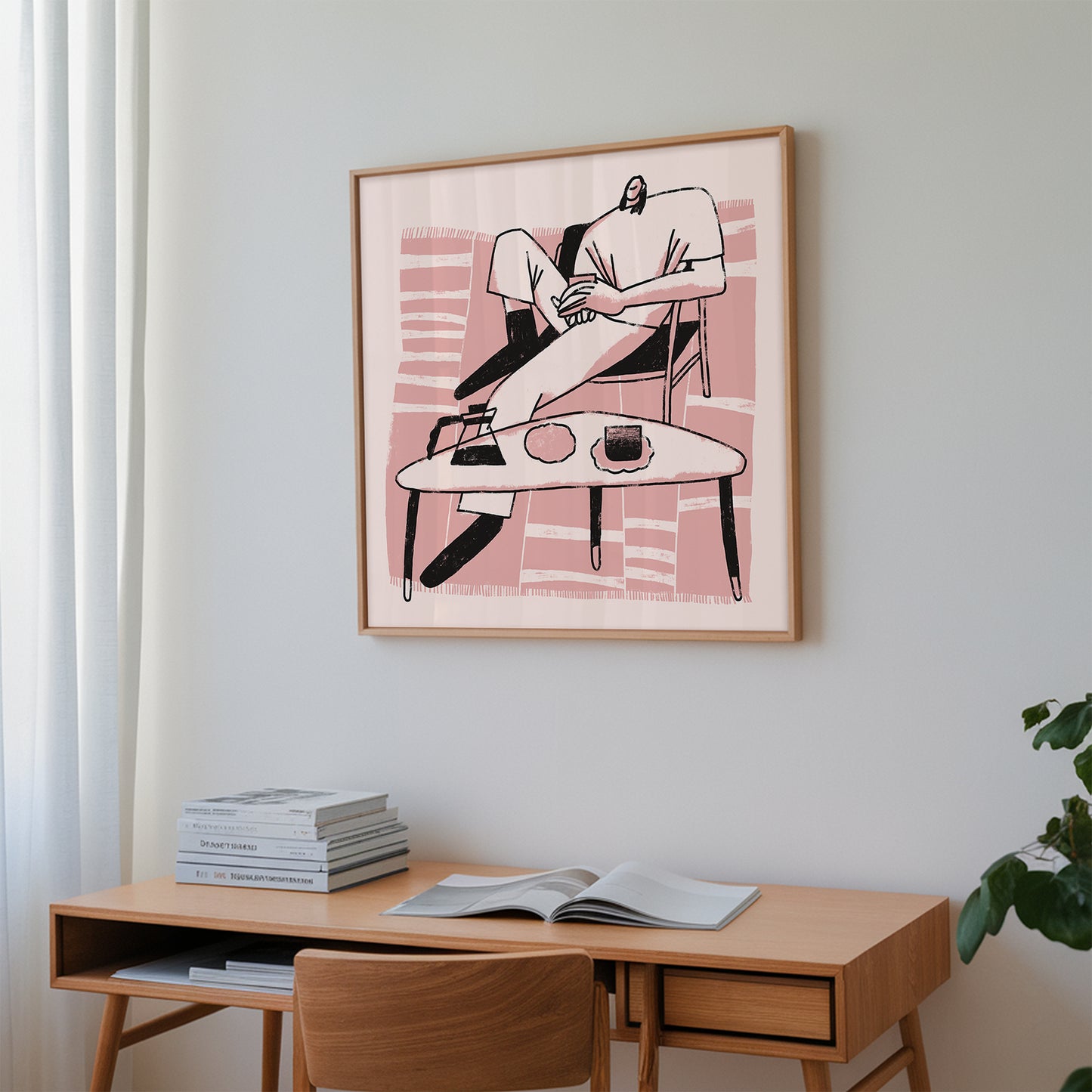 Framed pint artwork on a wall above a wooden desk with books and an open magazine.