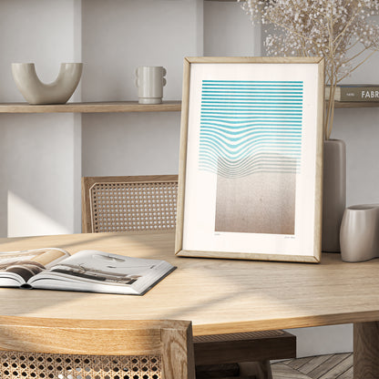 Limited edition poster Volna in teal and gold in a wooden frame on the table