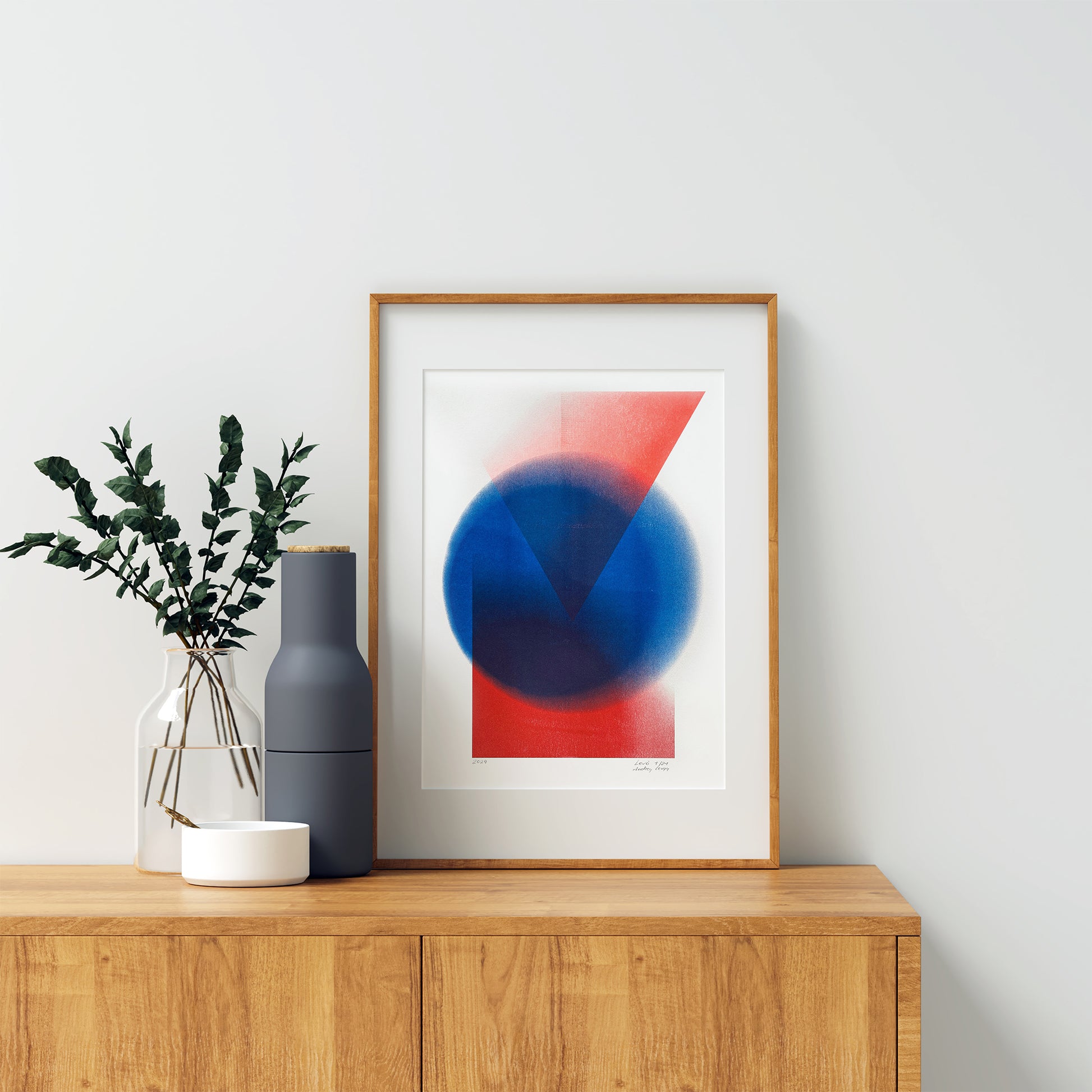 Limited edition riso poster Diviny in a wooden frame on the chest of drawers