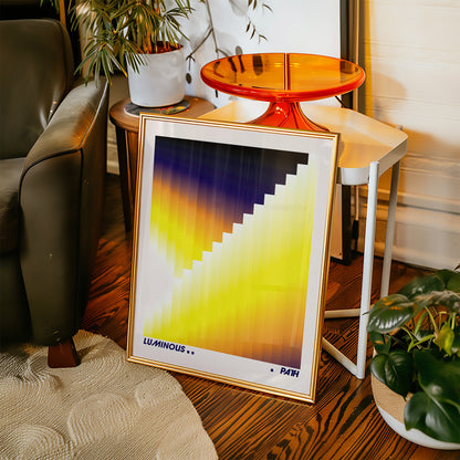 Framed abstract art print on a wooden floor with a chair and plants in the background