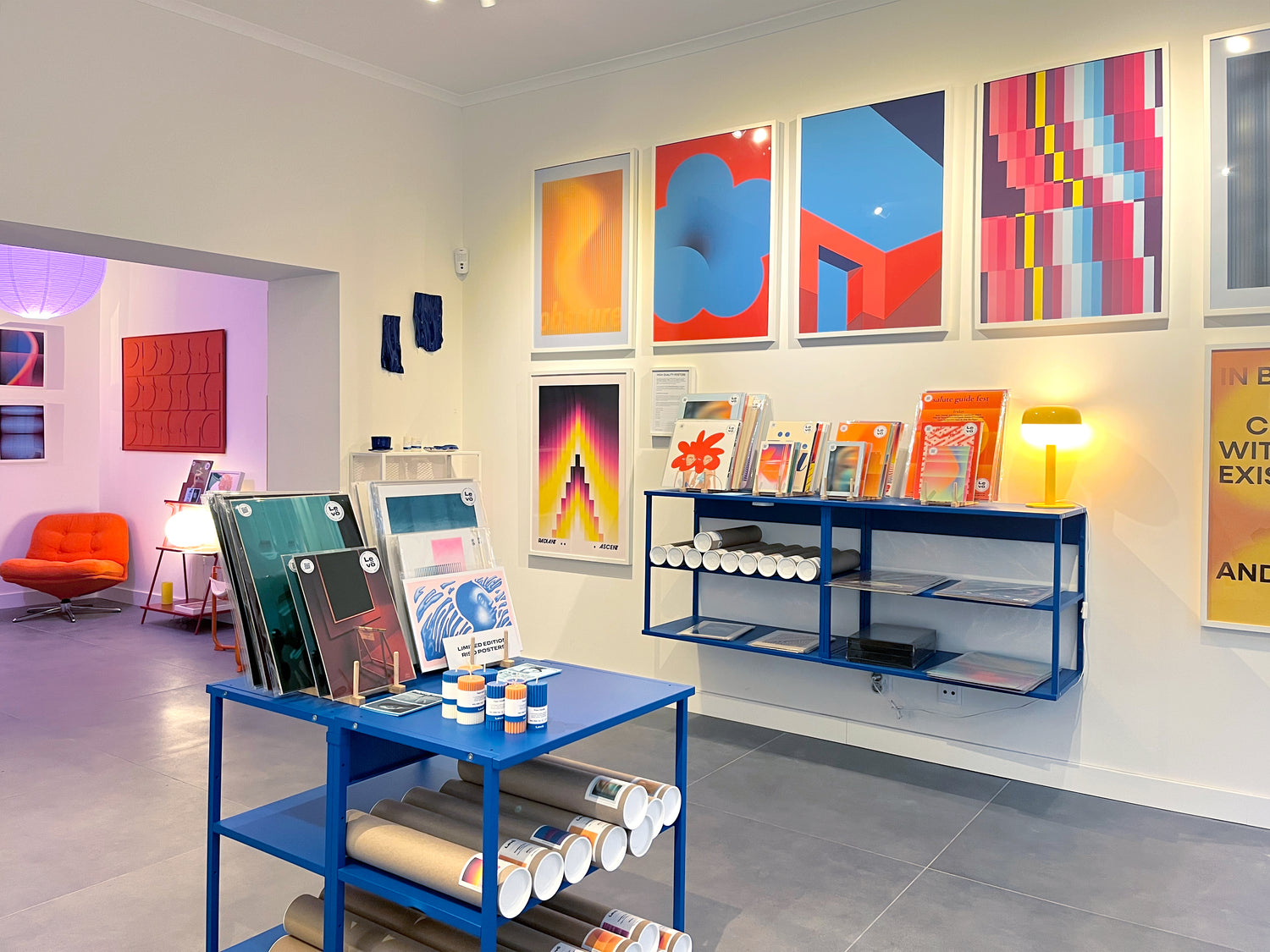 Art gallery in Lisbon with colorful abstract paintings on the wall and a display table with art supplies.