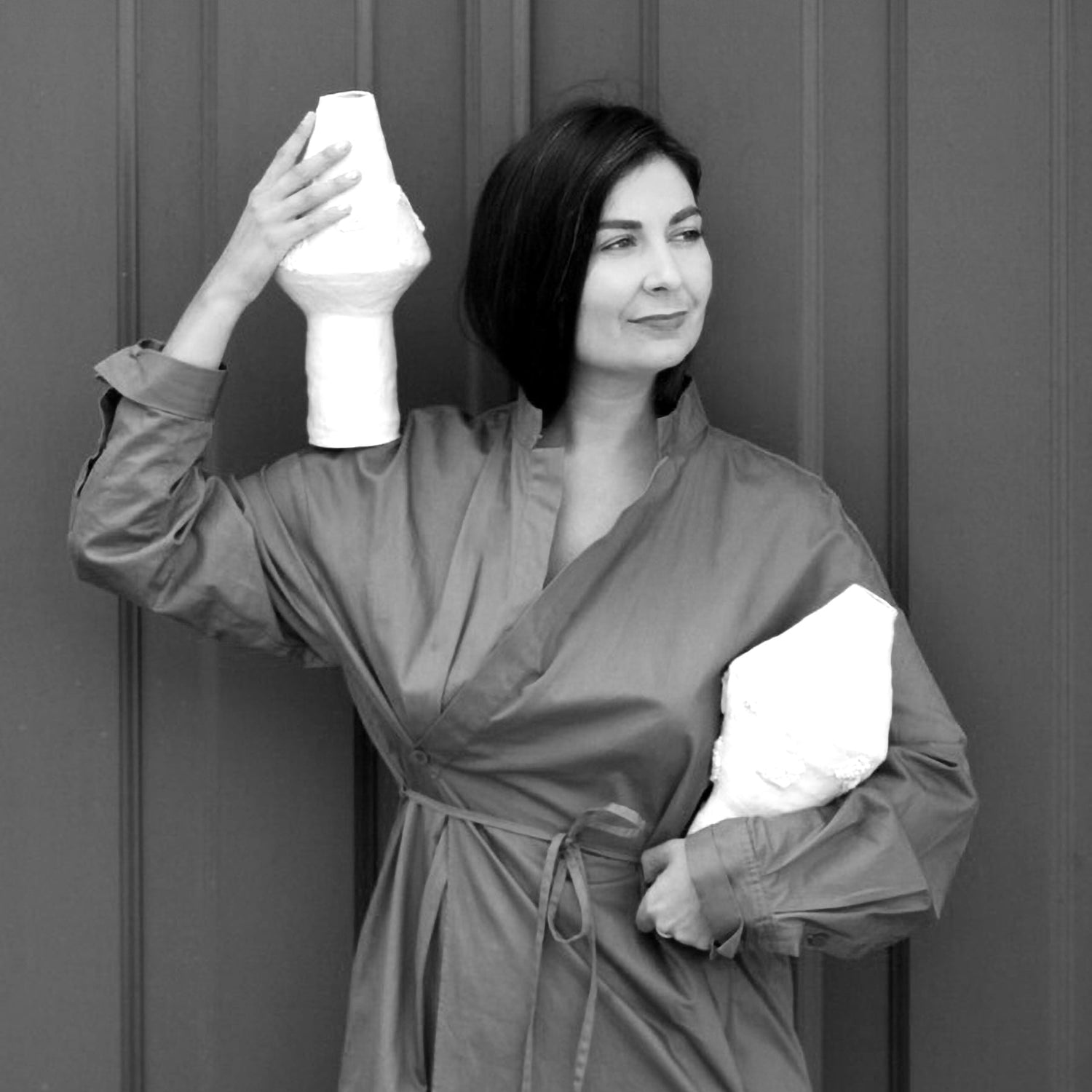 Anna De holding a ceramic vases against a plain background Levo in Lisbon